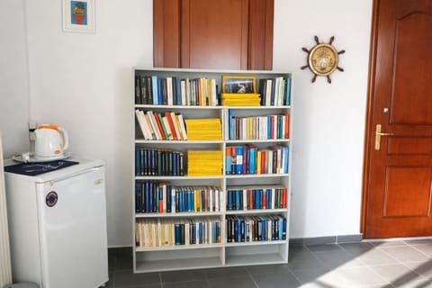 Practical corner featuring a bookcase, small fridge, a kettle and storage space, ideal for added comfort during short or extended stays