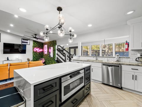 Your sleek modern kitchen flows seamlessly into the living space, featuring granite counters, stainless appliances, and dramatic pendant lighting for memorable evenings.