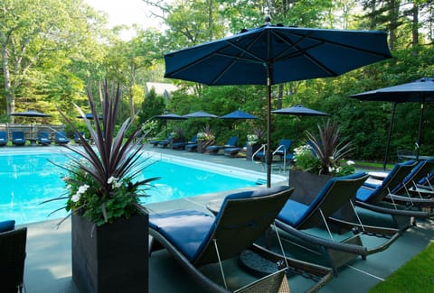 A tranquil poolside scene adorned with stylish umbrellas and comfortable lounge chairs, perfect for soaking up the sun at this coastal retreat.