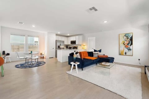 Spacious living room with a cozy navy sectional, bright natural light, and a 55” TV for streaming your favorite shows. This open-concept space flows into the kitchen and dining areas, creating the perfect place to unwind, gather, and relax.