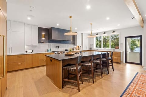This chef’s kitchen boasts Wolf appliances, dual dishwashers, twin Sub-Zero fridge and freezer, warming drawer, wine fridge, and a sleek island with seating. Marble and wood finishes pair with designer lighting for a refined, modern feel.