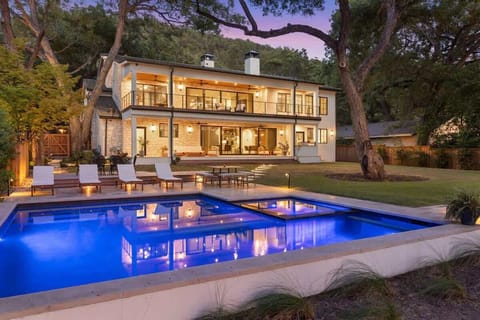An architectural gem set against a lush backdrop, this estate features a glowing pool, expansive balconies, and elegant stonework—blending modern luxury with timeless charm for an unforgettable retreat.