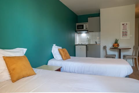 A bright studio layout with twin beds and an open living area for a comfortable stay.