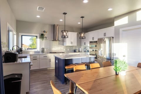 Modern stainless steel kitchen designed for cooking for large group with seamless flow to multiple dining tables and effortless entertaining.
