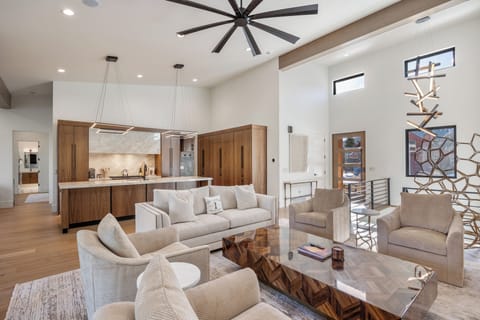 Spacious main-floor living room featuring plush seating, high ceilings, and an open layout that flows seamlessly into the kitchen and dining areas—ideal for gathering and relaxing.