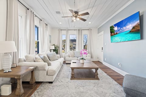 Bright, modern living room with cozy sofas, big windows, and a wall-mounted TV, perfect for relaxing after a day out.