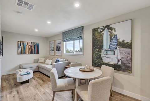 Cozy living area w/ sectional seating, round dining table & coastal artwork for a relaxed hangout