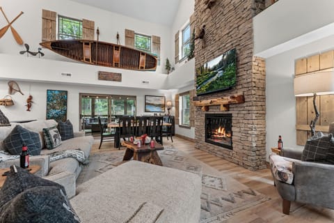 Gather beneath soaring ceilings in a stunning great room featuring a floor-to-ceiling stone fireplace, custom canoe décor, and space for everyone to relax together.