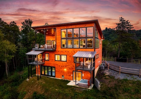 Modern multi-level cabin exterior at sunset, surrounded by mountain scenery
