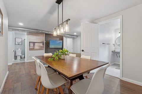 Stylish dining room with seating for six, modern pendant lighting, and abstract art—perfect for meals or remote work.