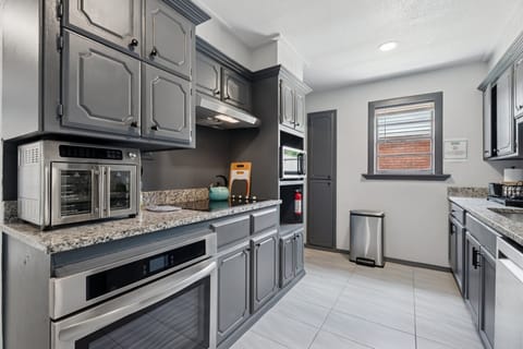 Fully equipped kitchen with modern appliances, granite counters, and classic gray cabinetry—everything you need to cook at home.