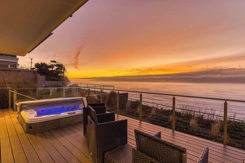 Relax on the expansive deck featuring a private hot tub and breathtaking oceanfront sunset views.
