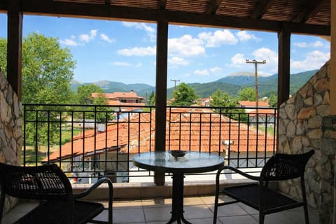 Covered Balcony with Outdoor Seating and Open Village Views
Shaded balcony with table and chairs, offering relaxing views over the village rooftops and surrounding greenery.