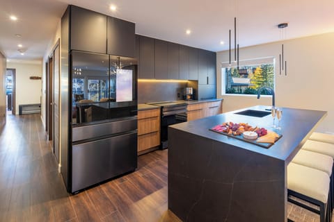 You'll love preparing meals in this stunning modern kitchen featuring sleek dark cabinetry, premium appliances, and a spacious island perfect for entertaining.