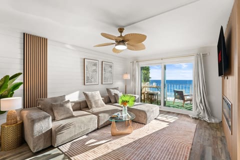 Open plan living space looking over the pool, beach and sea, with extra large couch seating the whole group