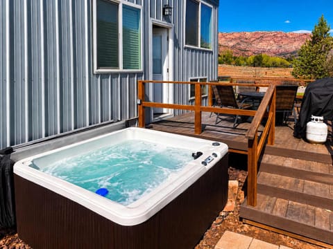 Relax in the private hot tub after a day exploring Southern Utah. The spacious deck features outdoor dining, a BBQ grill, and beautiful red rock scenery, creating the perfect place to unwind morning or night.
