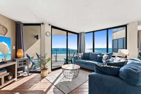 Gulf-front living room with panoramic ocean views, private balcony access, and a queen-size sleeper sofa for extra guests.