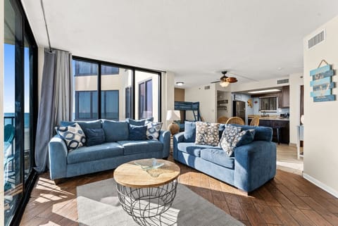 Bright Gulf-front living room featuring a comfortable queen-size sleeper sofa, coastal décor, and floor-to-ceiling windows with stunning views.