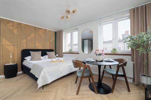 Bright studio space with a sleeping area, dining table, and elegant wall décor.