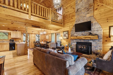 Open-concept living area with a stone fireplace, leather seating, and loft views.