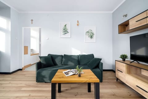 Bright living room with green sofa, wooden coffee table, and wall shelving.