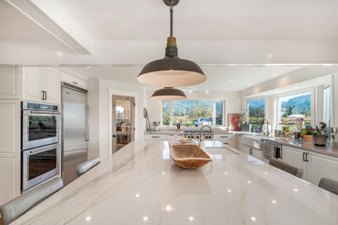 Your gourmet kitchen awaits with gleaming countertops, professional appliances, and stunning mountain views through expansive windows.