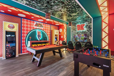 Enjoy a colorful Super Mario themed game room designed for endless fun, featuring arcade machines, a pool table, foosball, gaming chairs, and a wall-mounted TV. Bright colors, playful character details, and fun lighting create the perfect entertainme