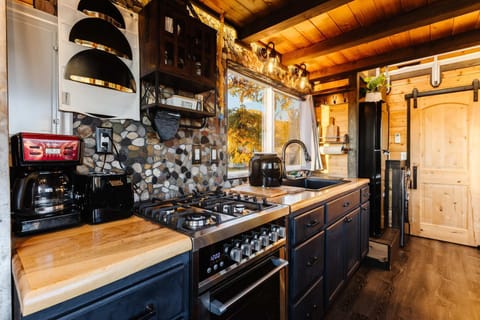 Fully equipped kitchen with wood countertops, modern appliances, a gas range, and stylish cabinetry. Bright windows and thoughtful design make cooking easy, functional, and enjoyable in this cozy tiny home.