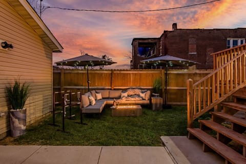 Enchanted Backyard Lounge: Unwind on the plush sectional sofa by the cozy fire pit table under a canopy of twinkling string lights—the perfect end to your evening.