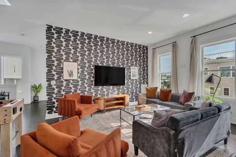 Open-concept living room with foosball table, plush seating, and a bright, modern kitchen. | Unit A