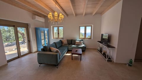 Living room at Achilles Cottage with sea-view windows, brass chandelier and sliding doors to the garden