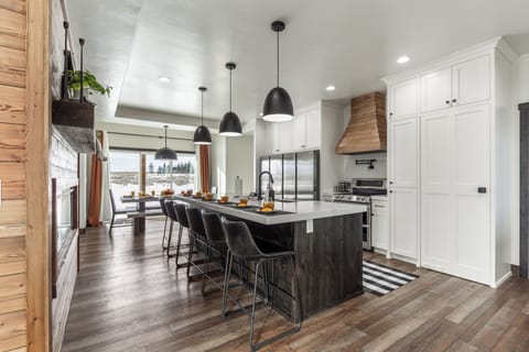 This stunning kitchen features an oversized island, chef-style range, dual refrigerators, and a hidden walk-in pantry tucked seamlessly into the cabinetry—offering incredible storage without sacrificing style.