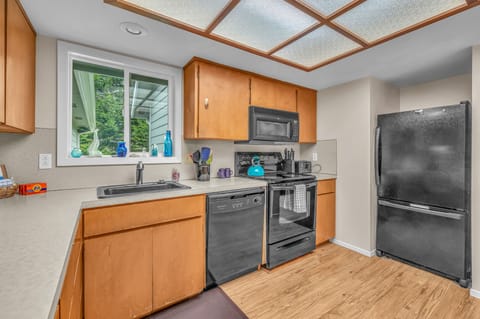 Your fully equipped kitchen features modern appliances, warm wood cabinetry, and a sunny window overlooking lush greenery for inspiring meal prep.