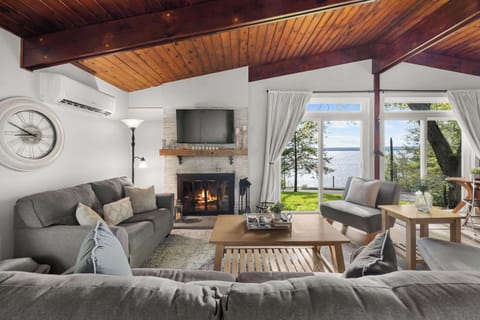 Inviting main living room with lake views, vaulted wood ceilings, comfortable seating, and a cozy fireplace.