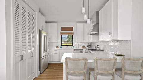 Your sleek white kitchen awaits with modern appliances and elegant pendant lighting for memorable meal preparation.