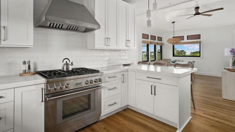 Step into your dream kitchen with pristine white cabinetry, professional-grade appliances, and stunning views beyond.
