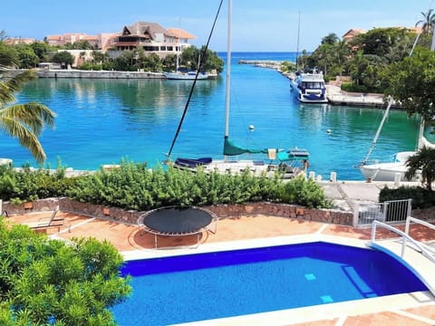 “Relájate con esta espectacular vista a la marina de Puerto Aventuras desde la piscina del condominio. Amaneceres de postal y aguas turquesa a tus pies.”