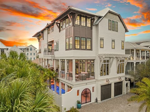Stunning coastal property with elegant architecture and tropical landscaping, set against a breathtaking sunset sky in a peaceful neighborhood.