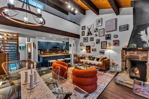 Open-concept living, dining, and kitchen area, modernist swivel chairs, wood-burning fireplace, vaulted ceilings, access to balcony, main floor