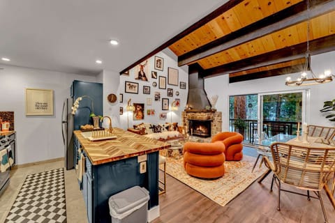 Open-concept living, dining, and kitchen area, modernist swivel chairs, wood-burning fireplace, vaulted ceilings, access to balcony, main floor