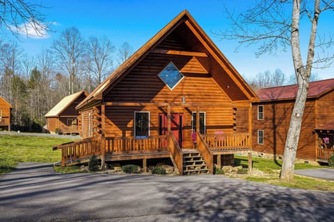 A charming log cabin featuring rustic wood construction with a distinctive diamond window accent and welcoming front deck.