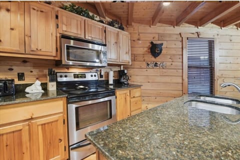 Your fully equipped kitchen features granite counters, stainless appliances, and rustic log cabin charm perfect for preparing meals.