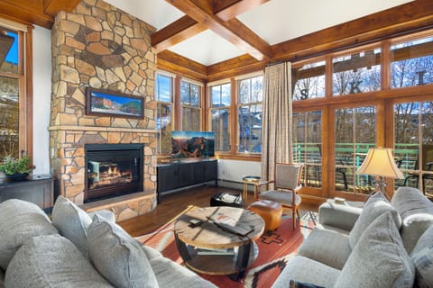 Cozy up by your stone fireplace while natural light pours through floor-to-ceiling windows, creating the perfect mountain retreat atmosphere.