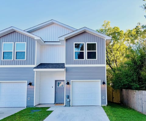Modern townhouse exterior with garage, driveway, and fenced green space