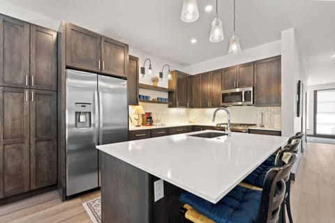 Full kitchen with stainless steel appliances and breakfast bar with seating for three.