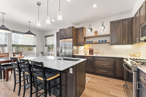 Full kitchen with stainless steel appliances and breakfast bar with seating for three.