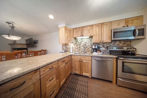 Your fully equipped kitchen features warm wood cabinets, granite countertops, and stainless steel appliances for comfortable home cooking during your stay.