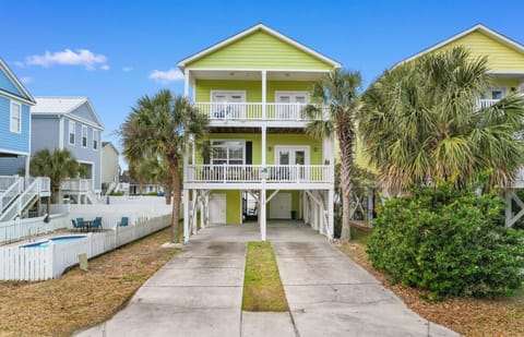 Bright coastal home with multiple balconies and tropical palms creates the perfect beach getaway atmosphere in this charming neighborhood.