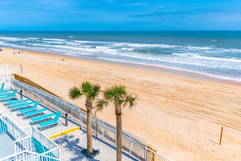 Relax on the beachfront with lounge chairs and palm trees, just steps from the pristine sandy shores of Ormond Beach.