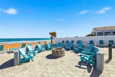 The cozy fire pit surrounded by bright blue Adirondack chairs invites guests to unwind while enjoying spectacular ocean views and the soothing sounds of the waves crashing on the shore.